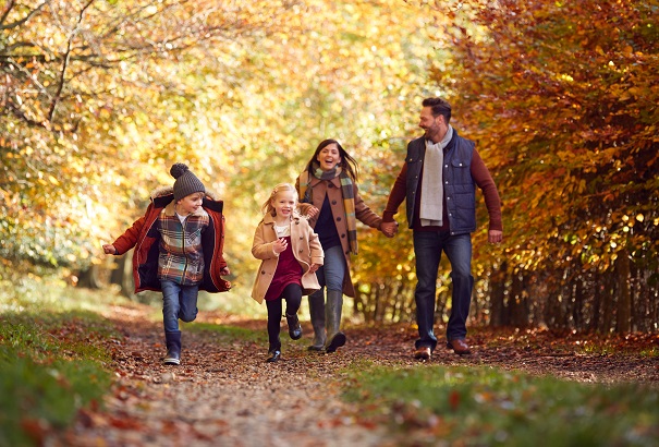 Happy family running through the woods in autumn