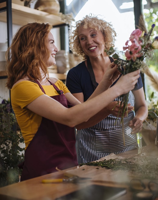 Two women discussing their small business health insurance in their flower shop